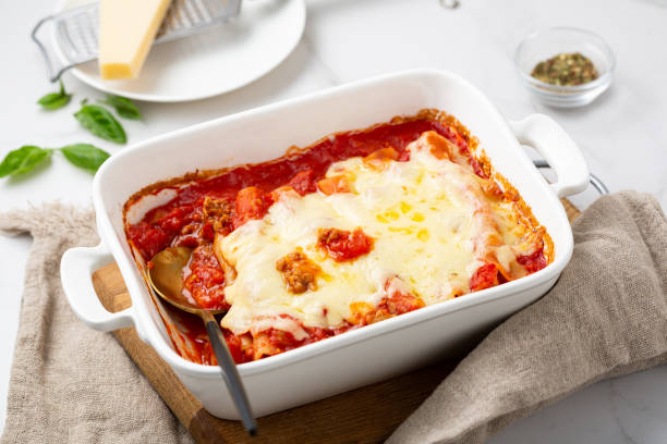 close up of baked pasta canelloni with beef cheese tomato food in white dish stock photo
