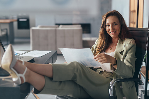 Woman working at home with her feet up on her desk.