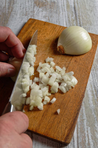 istock Close up of man hands cutting an onion into cubes 1403273419