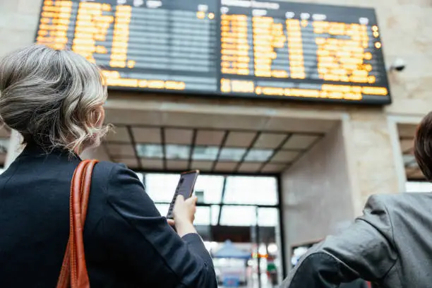 Photo of A woman is checking departures board at the railway station