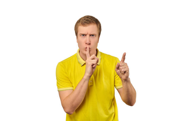 노란색 티셔츠를 입은 재미있는 남성은 조용하고, 침묵의 제스처, 흰색 배경을 요구합니다. - finger on lips shhhh privacy whispering 뉴스 사진 이미지