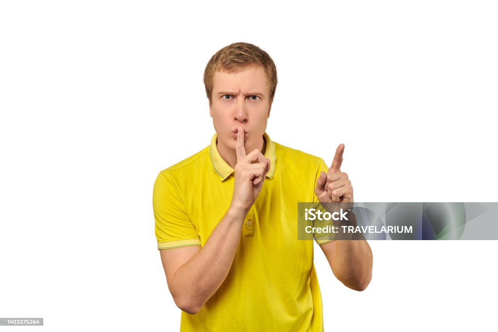 Funny male in yellow T-shirt asking to be quiet, silence gesture, white background Funny male in yellow T-shirt asking to be quiet, silence gesture isolated on white background. Young man saying Shhh, keep quiet, please and making silence gesture, request for silence 25-29 Years Stock Photo