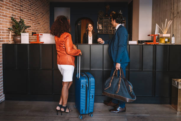 les gens d’affaires s’enregistrent à la réception de l’hôtel - hotel receptionist photos et images de collection