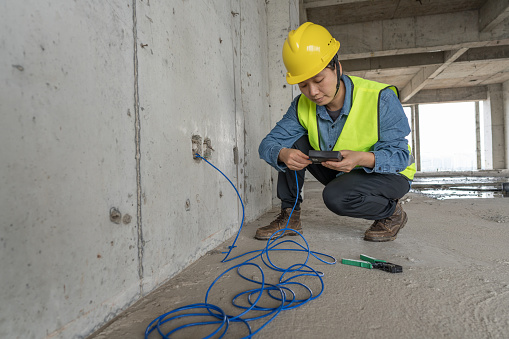 An Asian female engineering technician carries out network wiring on the construction site