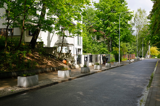 Gdynia, Poland - May 26, 2022: There is no car traffic on the street leading through a residential area. There is a lot of vegetation and trees here.