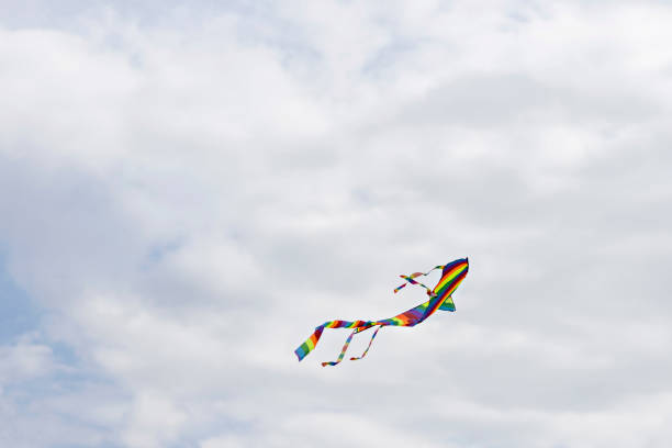 Colorful blue sky with white fluffy clouds and a flying colored kite.
