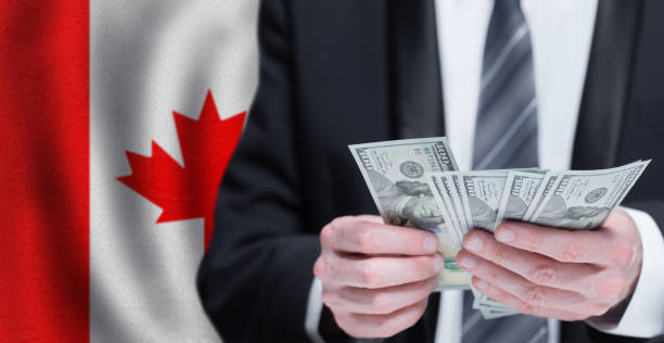 istock Hands holding dollar money on flag of Canada 1403280558