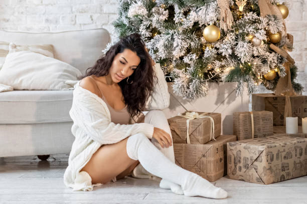 A happy young mulatto woman is sitting with gifts at the Christmas tree.Celebrating Christmas and New Year. Winter holidays. A happy young mulatto woman is sitting with gifts at the Christmas tree.Celebrating Christmas and New Year. Winter holidays beautiful mulatto women stock pictures, royalty-free photos & images