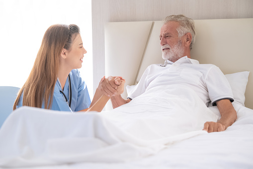 Home care and healthy insurance. female doctor embracing encouraging happy senior male patient in hospital.