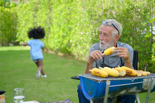 Family holiday activities with grandfather, mother and children with camping. bbq grill and play in the yard together happily on vacation.