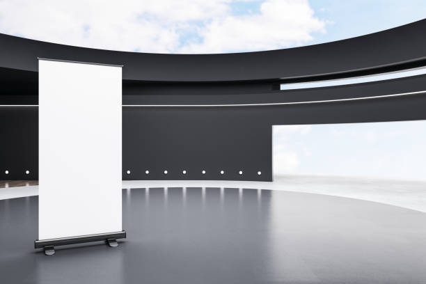 istock Open ceiling with sky view gallery interior with empty white roll up mock up poster and concrete flooring. Art and exhibition design concept. 3D Rendering. 1403288203