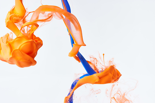 Abstract blue and orange ink drop over light gray background
