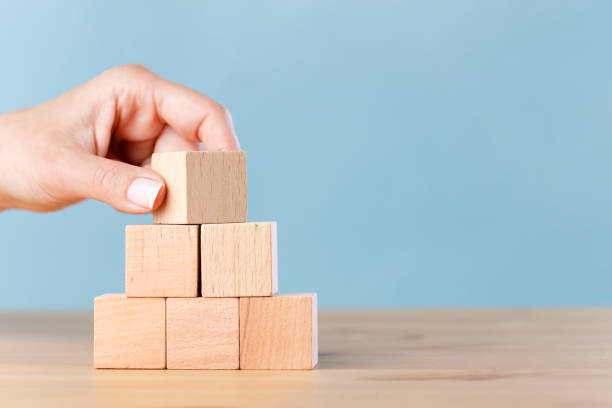 Woman hand flips blank wooden cube on top pyramid Woman hand flips blank wooden cube on top pyramid, place your own creative success symbols building block stock pictures, royalty-free photos & images