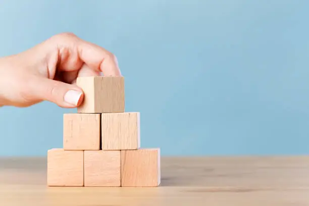 Photo of Woman hand flips blank wooden cube on top pyramid