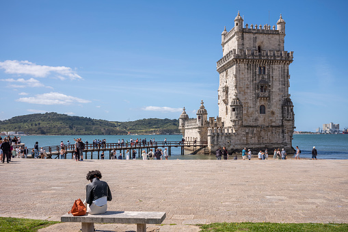 Lisbon, Portugal - May 24, 2022: Belem Tower (Torre de Belem) on a sunny day with tourists. UNESCO World Heritage Site from the early 16th century.