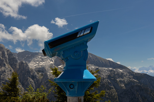 A bright telescope against the backdrop of the Alpine mountains allows you to see the peaks and valleys in detail.