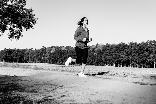 view on woman running in landscape in the afternoon sun, black and white image
