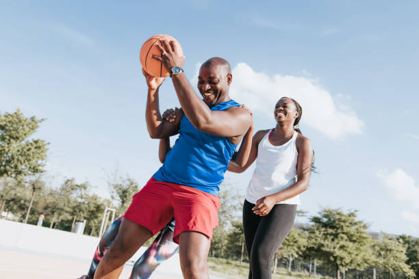 african family playing basketball together at sunny day stock photo