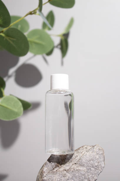 istock Cosmetic bottle with tonic water on stone stand with branch eucalyptus on grey background. Natural cosmetics concept, skin care product. Beauty concept for face body care 1403293832