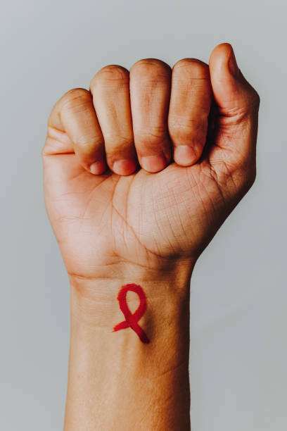 красная лента осведомленности о спиде, нарисованная на его запястье - aids awareness ribbon фотографии стоковые фото и изображения