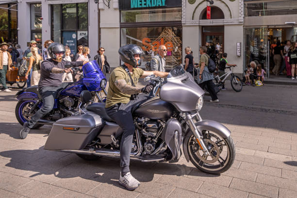 Two young men showing their large motorbikes in a pedestrian street in the center of Copenhagen