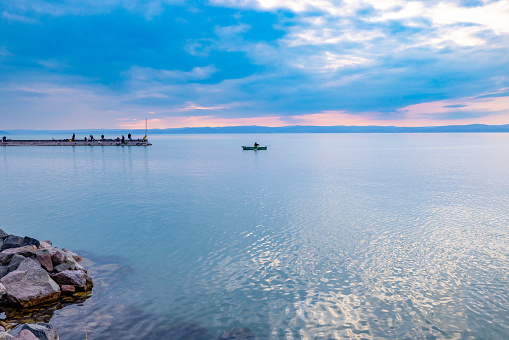 Scenic view of distant boat moving in lake against cloudy sky during sunset