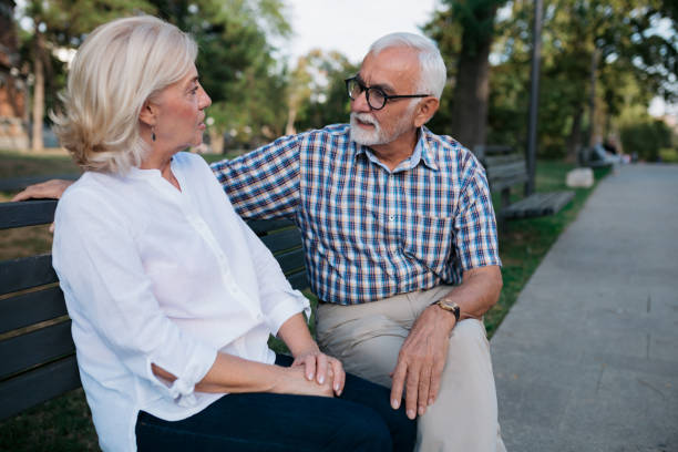 istock Senior married couple sitting on a park bench 1403296540