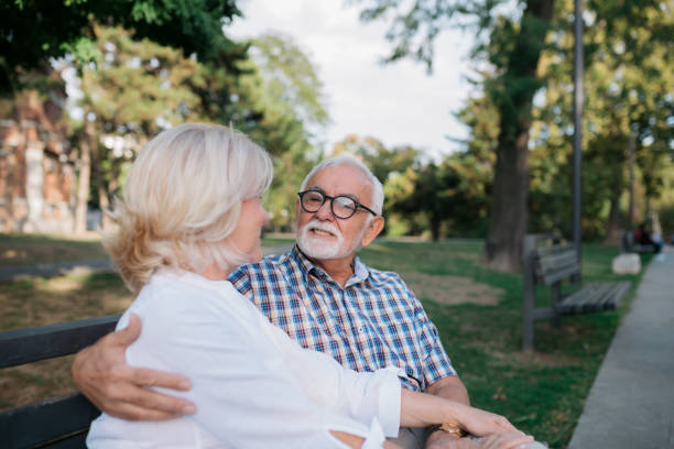 istock Senior married couple sitting on a park bench 1403296541