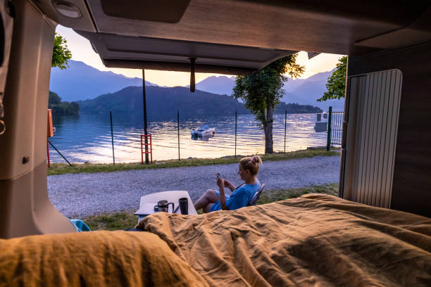 istock Woman sitting on chair using mobile phone beside camper van by Lake Como 1403296677