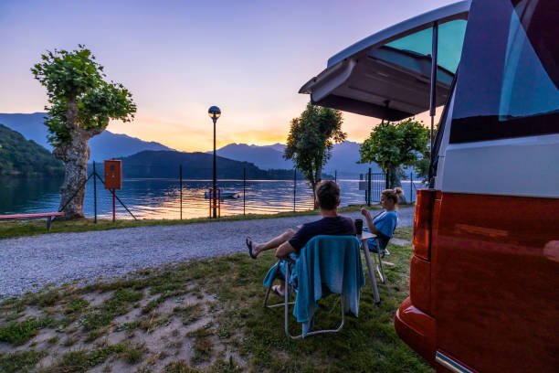 istock Couple sitting on chairs beside camper van by Lake Como at dusk 1403296793