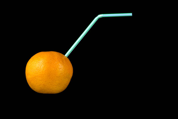Orange fruit pierced by drinking straw for juice drink concept
