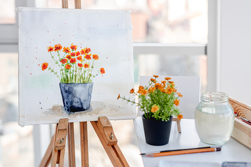 Messy artist working space with painting on easel in living room at home.