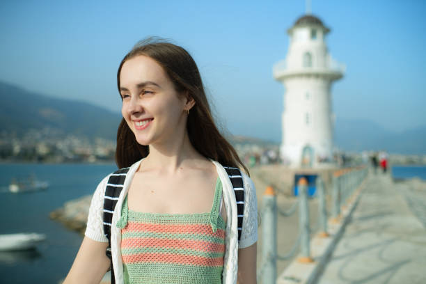 Young traveller enjoying a walk on a harbor with lighthouse