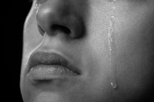 sad woman cries, shot a close up of female cheek with a tear drop, monochrome