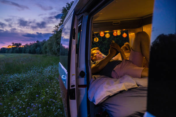 istock Man using smart phone while resting with woman in campervan during sunset 1403302158