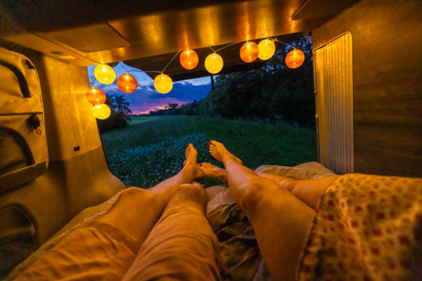 istock Couple lying down with view of field in illuminated campervan during sunset 1403302162