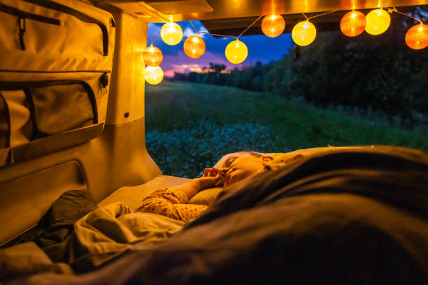 istock Woman sleeping in illuminated campervan against field during sunset 1403302244