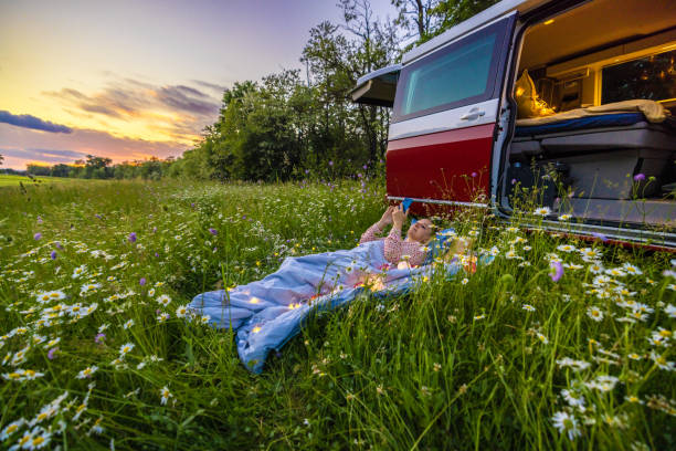 istock Carefree woman relaxing amidst plants while using mobile phone outside camper trailer 1403302324