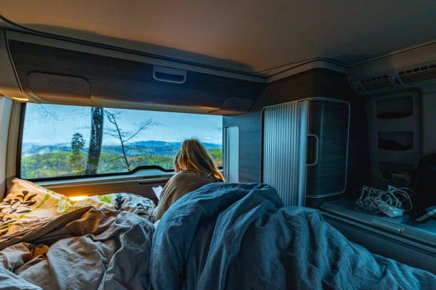 istock Carefree woman wrapped in blanket using phone while relaxing in camper trailer 1403302444