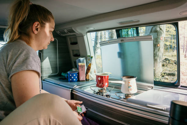 istock Mid adult woman making coffee by window while sitting in camper trailer 1403303054