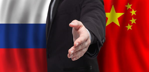 Russia and China concept. Male open hands for handshake on Russian and Chinese flag background