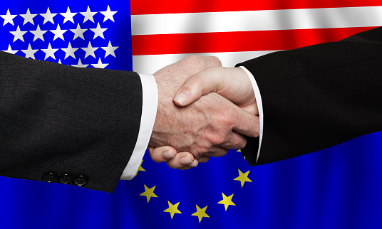 Hand holding USA and Great Britain flags on puzzle pieces joining together
