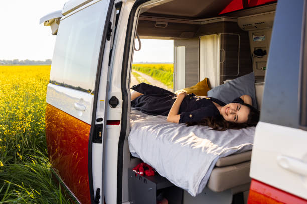 istock Woman with brown hair smiling and looking at camera while lying down in her van,view from outside,doors of van opened 1403303669