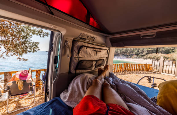 istock Barefoot man relaxing inside camper van while woman sitting on chair 1403304341