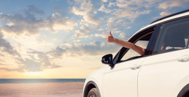 istock Happy man hand out window car against sky, clouds and sea 1403304630