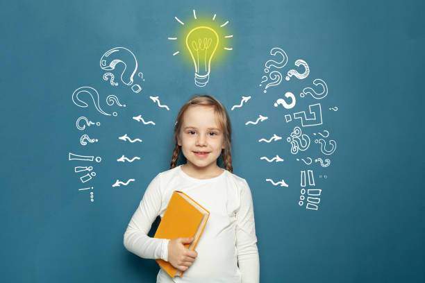 istock Cute happy kid with chalk drawing lightbulb, arrow and question mark. Education, success, idea and innovation concept 1403304998