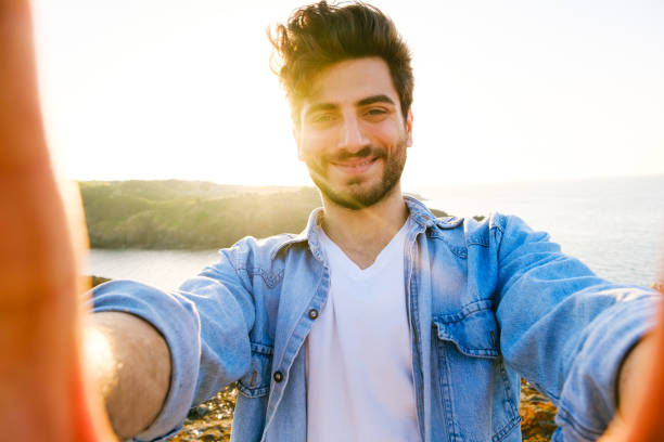 istock Happy man taking selfie using mobile phone at sunset on outdoor 1403305064