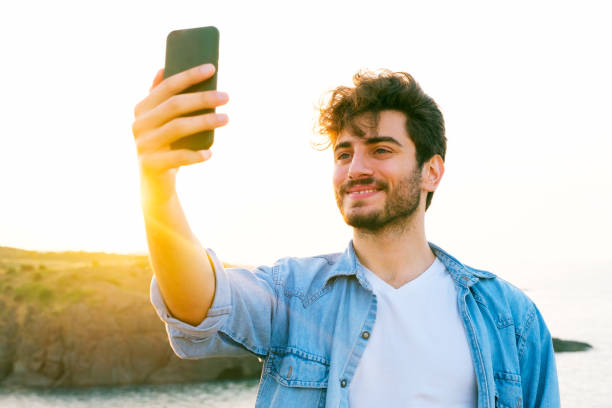istock Happy man taking selfie using mobile phone at sunset on outdoor 1403305134