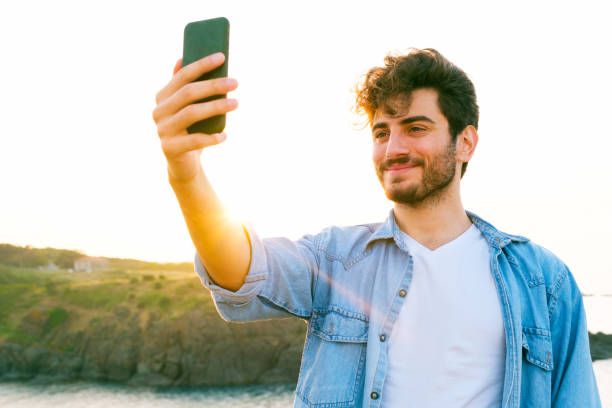 istock Happy man taking selfie using mobile phone at sunset on outdoor 1403305149