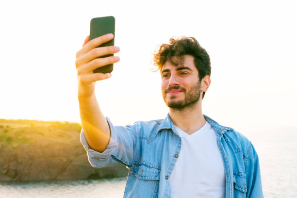 istock Happy man taking selfie using mobile phone at sunset on outdoor 1403305172